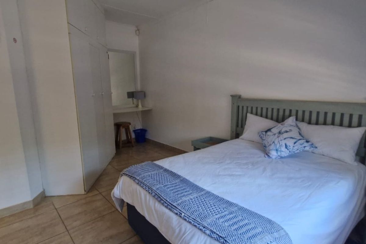 A functional bedroom featuring tiled flooring, built-in cupboards, and a built-in vanity area.