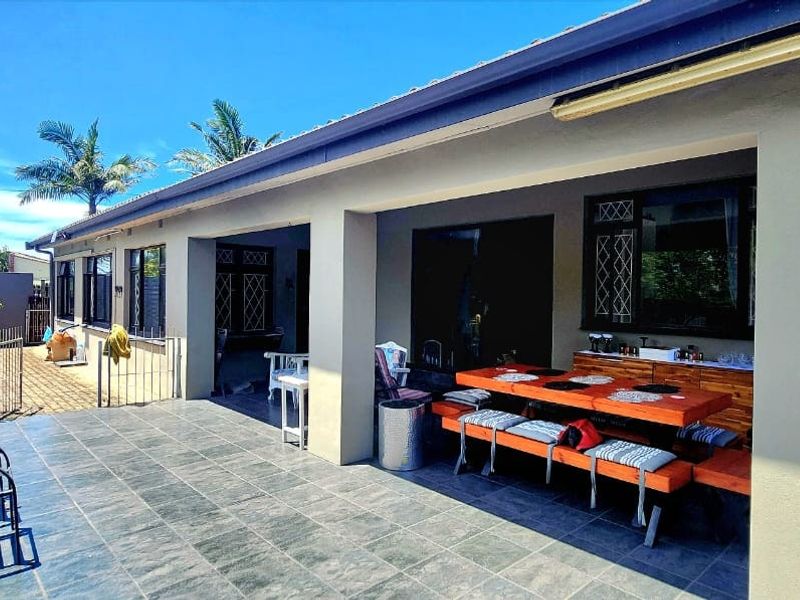 A spacious covered patio featuring tiled flooring, providing a seamless transition between indoor and outdoor living areas.