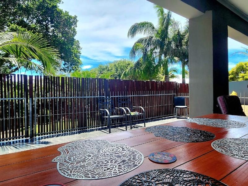 A spacious covered patio featuring tiled flooring and timber slat fencing, providing a comfortable outdoor entertainment area overlooking the garden.