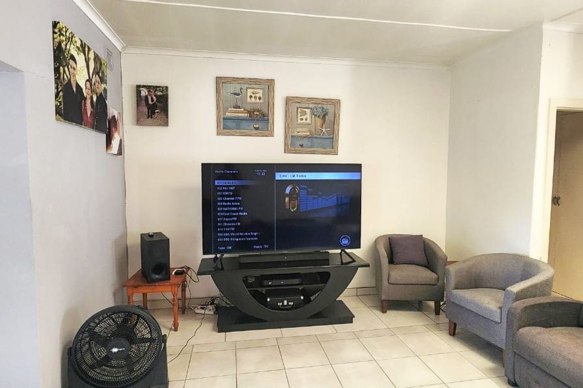 A functional living room featuring tiled flooring and a louvered door, providing a neutral base for potential interior updates.