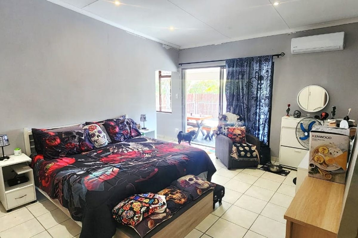 A bedroom featuring tiled flooring, a wall-mounted air conditioning unit, and a sliding glass door providing access to an outdoor area.
