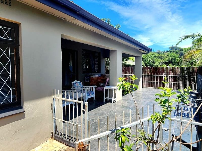 A covered outdoor patio area featuring tiled flooring, security gates, and timber slat fencing, providing a functional space for outdoor living.