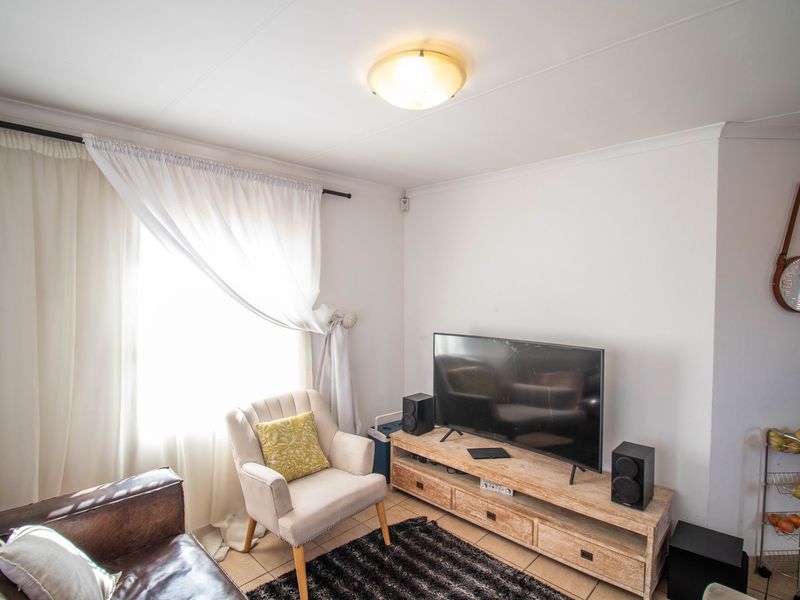 A bright living room featuring tiled flooring and a central ceiling light fixture, providing a functional and comfortable space for relaxation.