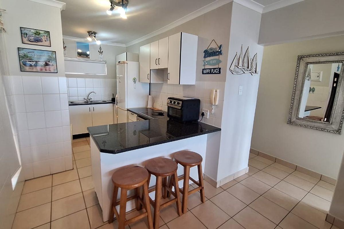 A functional kitchen featuring granite countertops, white cabinetry, a breakfast bar, and tiled flooring, offering a practical layout for daily use.