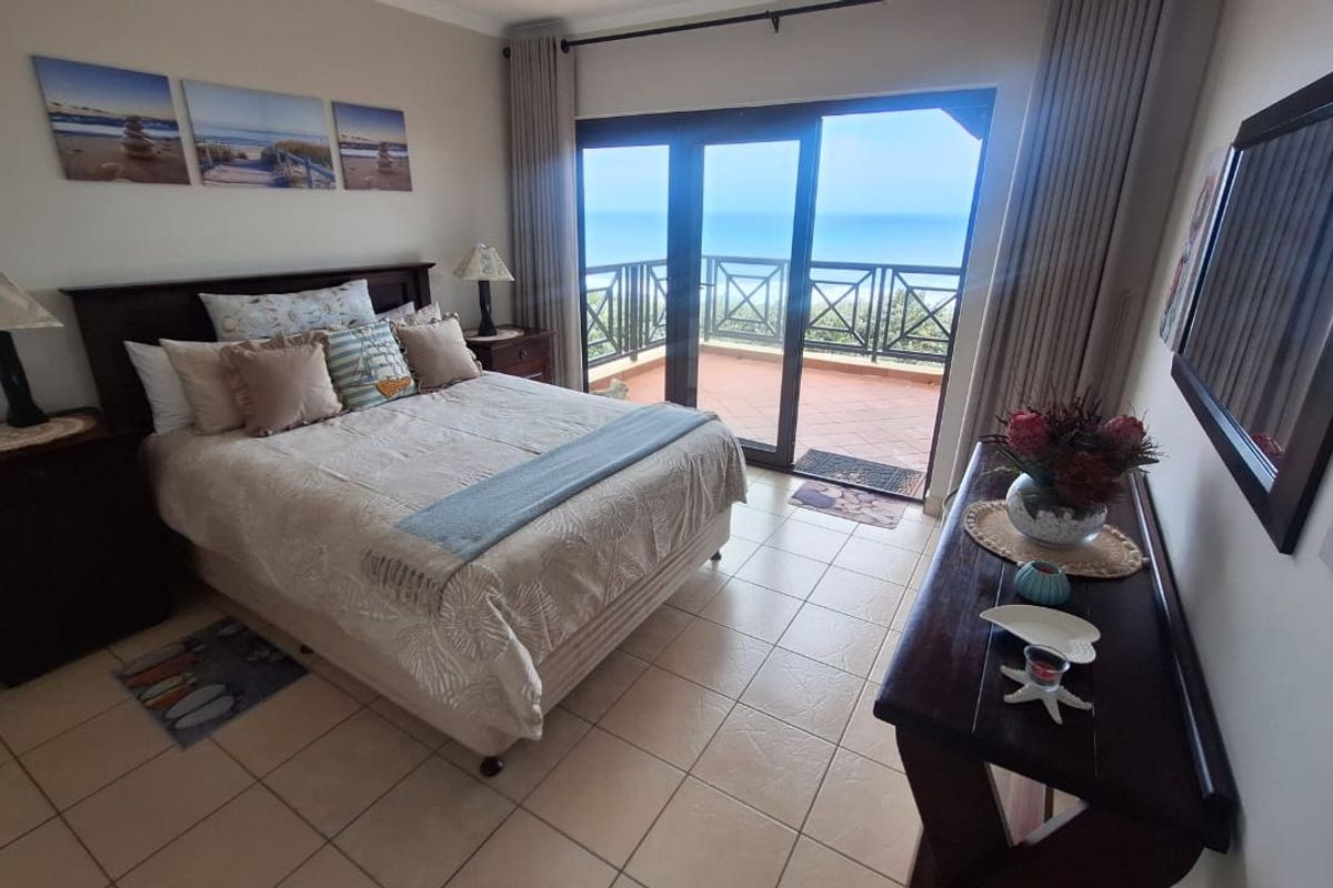 Spacious bedroom featuring tiled flooring and large sliding glass doors that open onto a private balcony with ocean views.