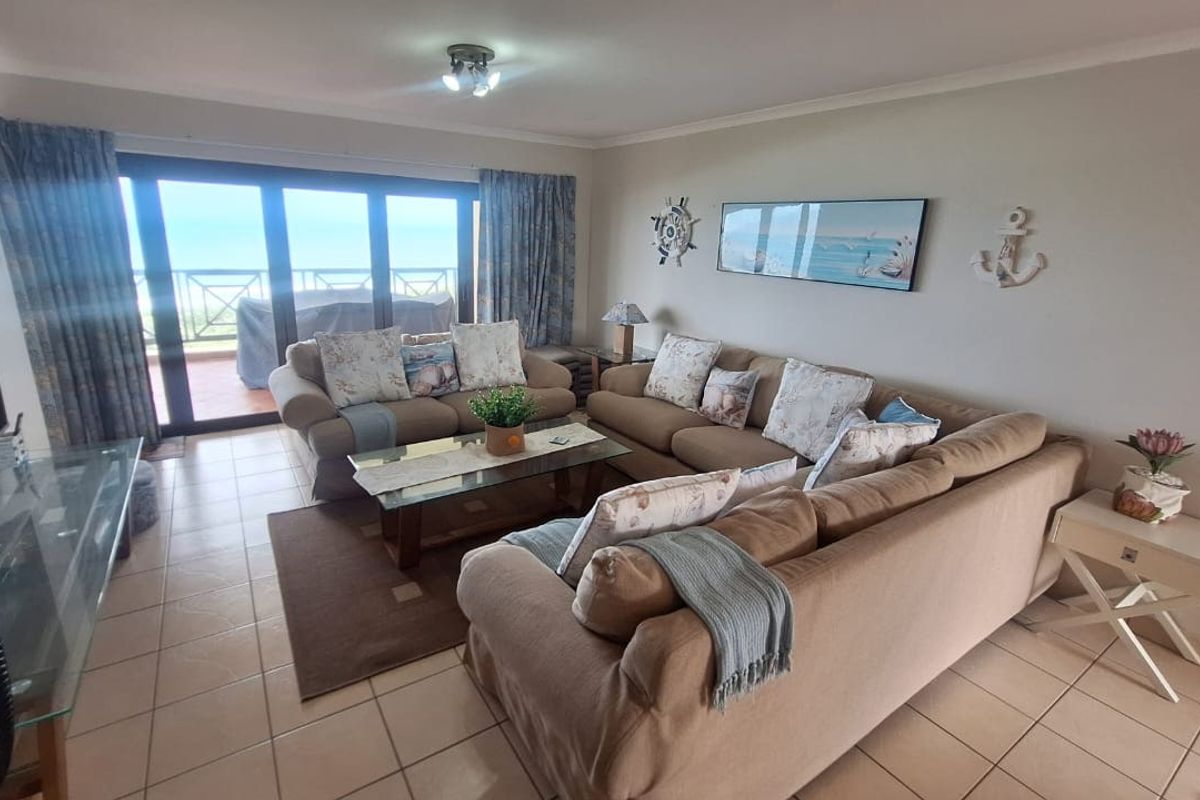 A spacious living room featuring tiled flooring and large sliding glass doors that provide access to an outdoor balcony area.