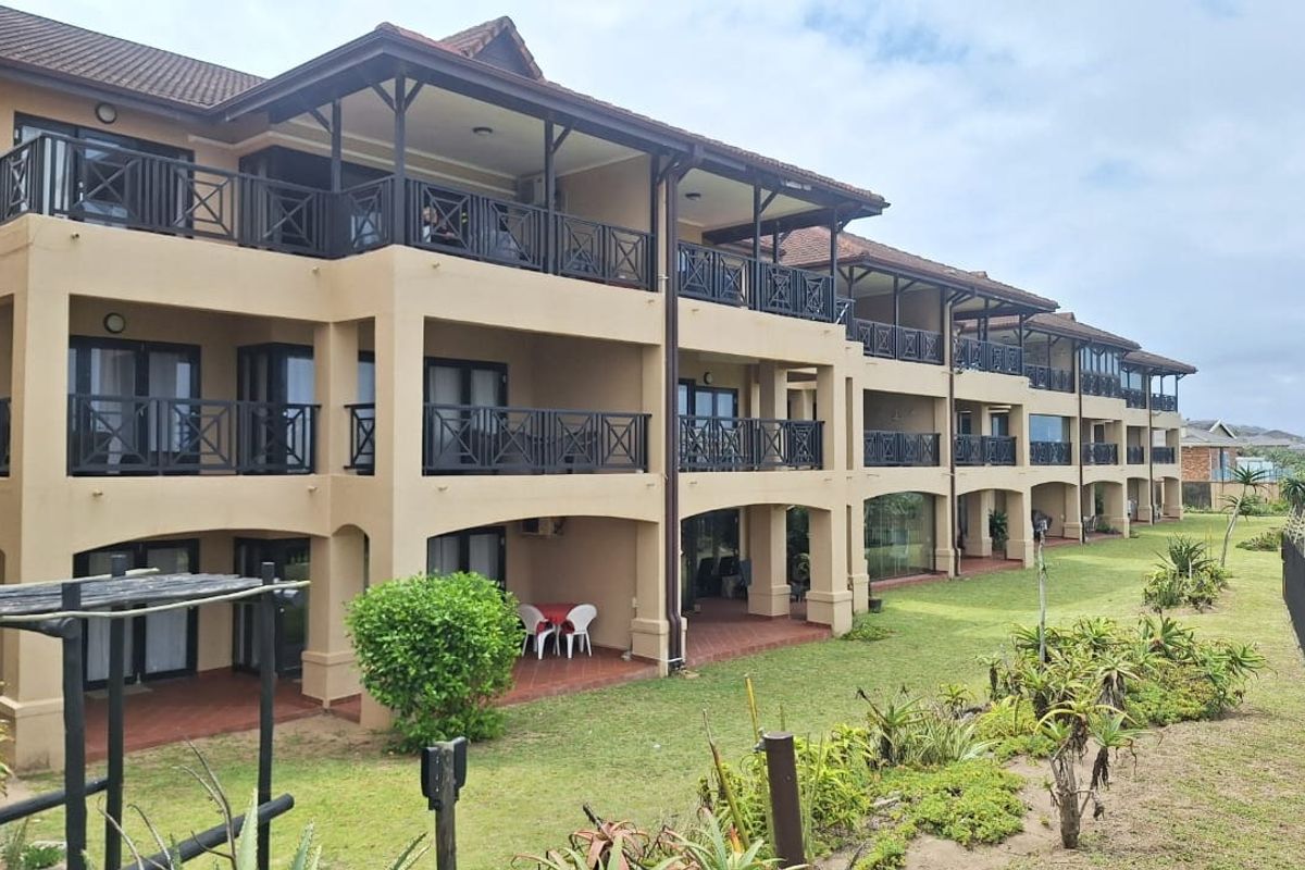 Rear elevation of a multi-story apartment complex featuring private balconies with metal railings, tiled flooring, and access to a shared garden area.
