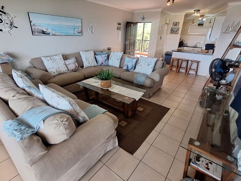 Open plan living area featuring tiled flooring and a functional kitchen with a breakfast bar, providing a comfortable and connected living space.