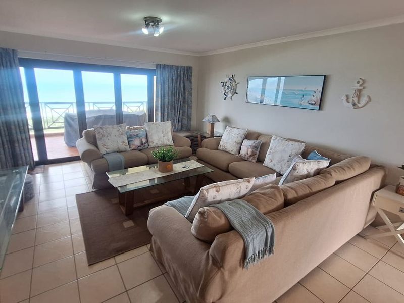 A spacious living room featuring tiled flooring and large sliding glass doors that provide access to an outdoor balcony area.