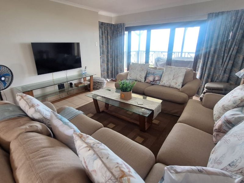 A comfortable living room featuring tiled flooring and large sliding glass doors that provide access to an outdoor balcony area.