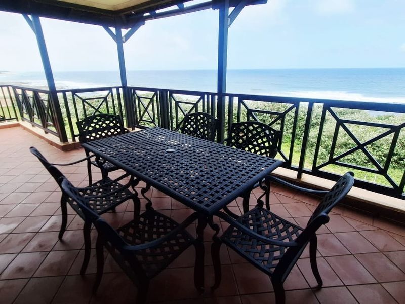 Spacious covered balcony featuring tiled flooring and a metal balustrade, offering expansive ocean views.
