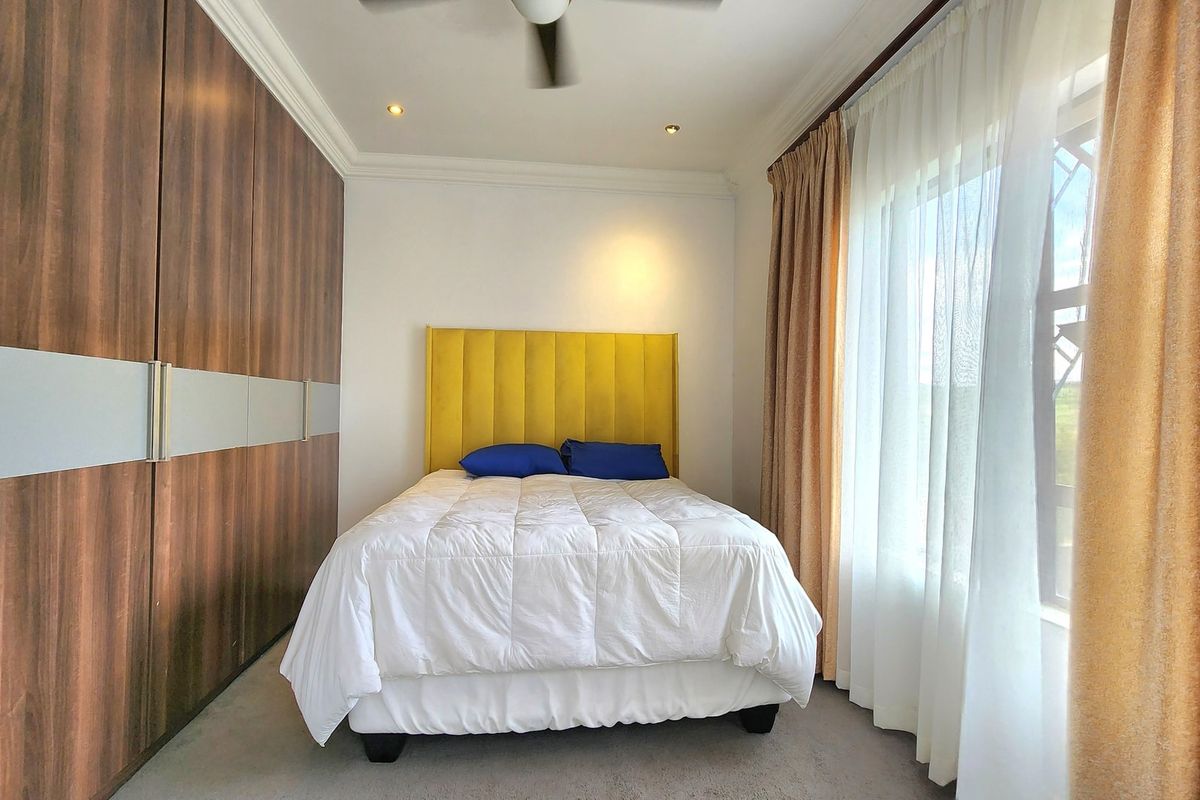 A well-maintained bedroom featuring floor-to-ceiling built-in cupboards, recessed downlighting, and a ceiling fan, offering a clean and functional living space.