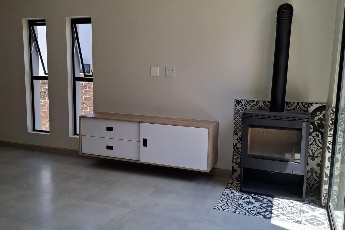 Modern living room featuring large format floor tiles, a built-in wood-burning fireplace with decorative tiling, and a wall-mounted floating media console.