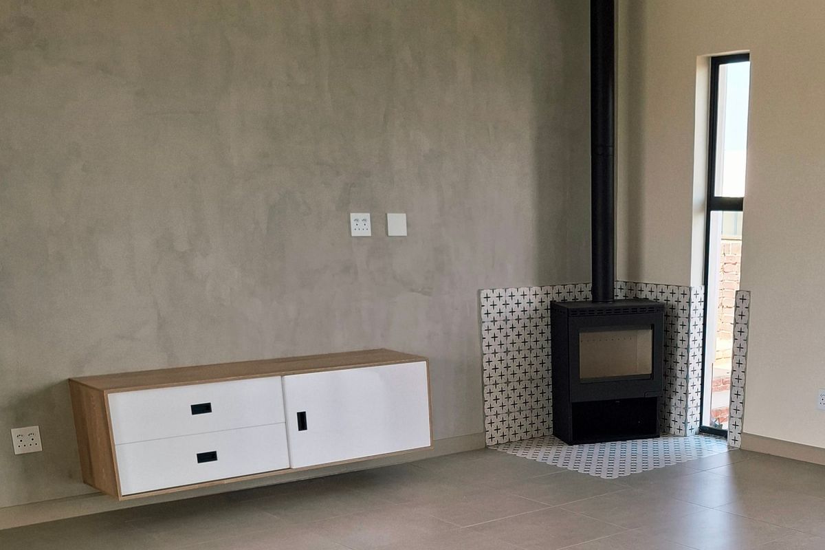 Modern living room featuring a sleek wood-burning fireplace with decorative tiling, floating cabinetry, and a split-system air conditioner.