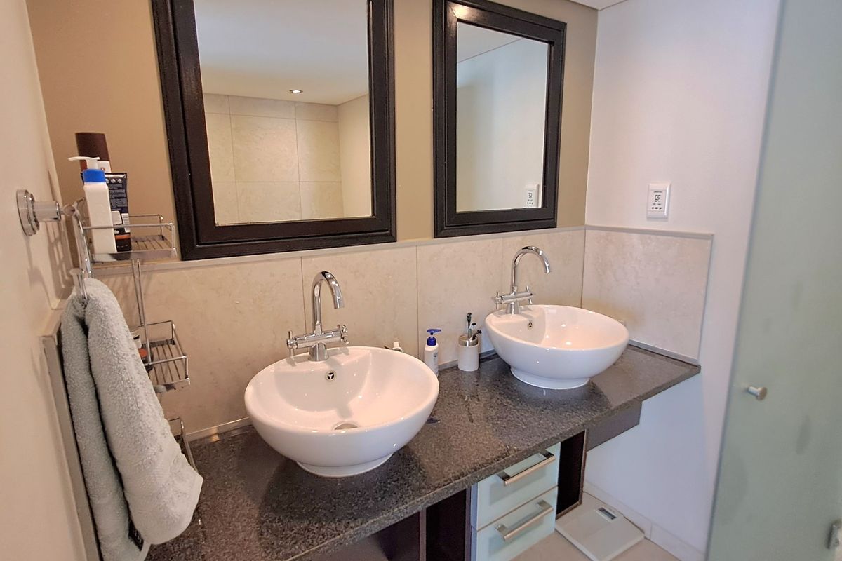 A modern bathroom featuring a double vanity with vessel sinks, granite countertops, and dual framed mirrors, providing a functional and stylish space.