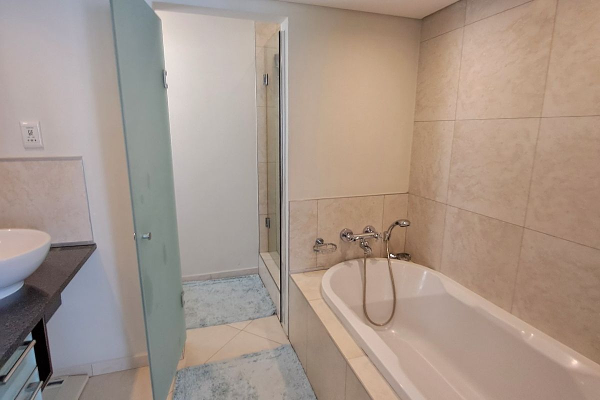 A modern bathroom featuring a built-in bathtub, tiled walls, a vanity with a vessel sink, and a separate shower enclosure.