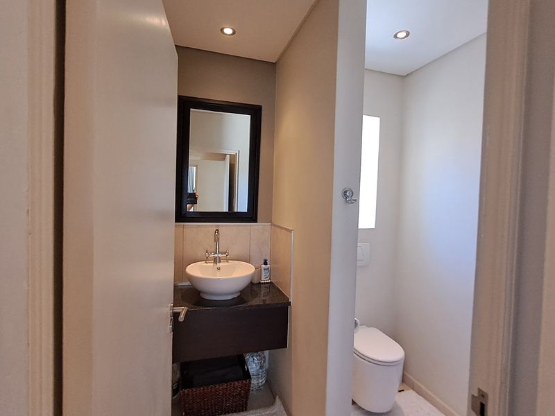 A modern guest bathroom featuring a vessel sink on a granite vanity and a separate enclosed toilet area with recessed lighting.
