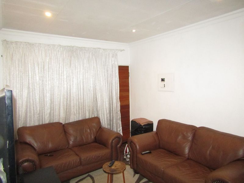 A living room featuring recessed downlights, cove cornicing, and a wall-mounted electrical distribution board.