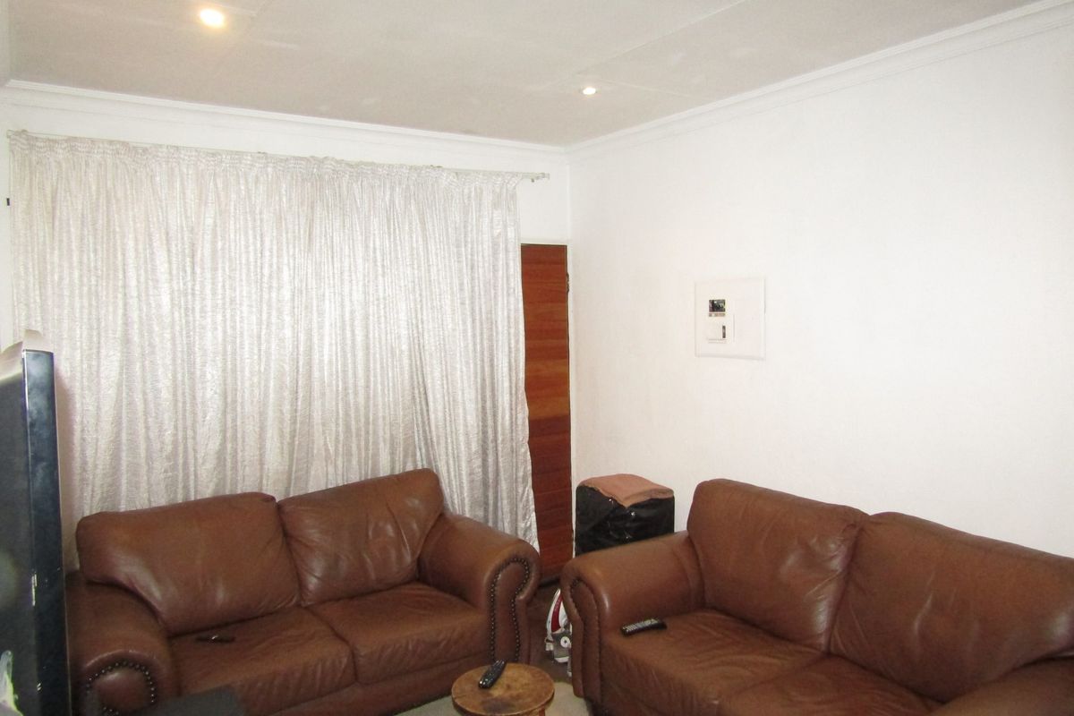A living room featuring recessed downlights, cove cornicing, and a wall-mounted electrical distribution board.