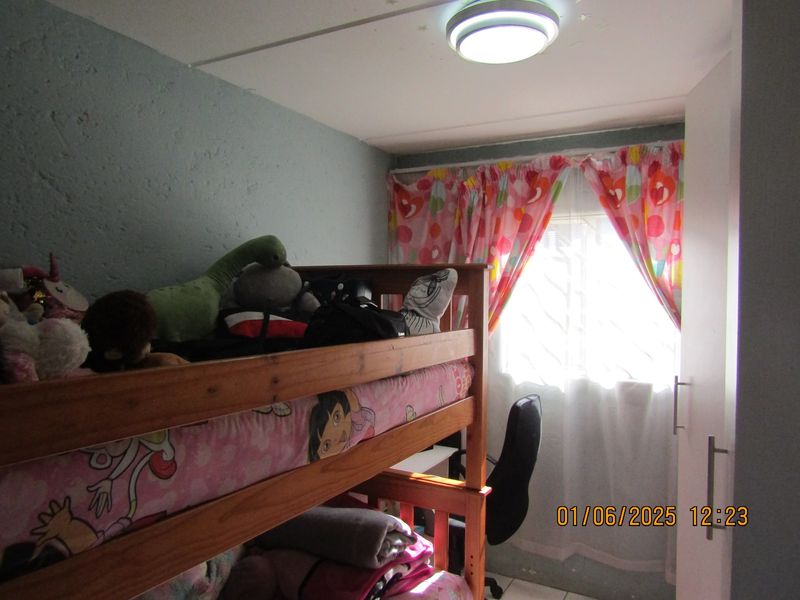 A compact bedroom featuring a built-in wardrobe and a window with natural light, providing a functional space for a child or guest.