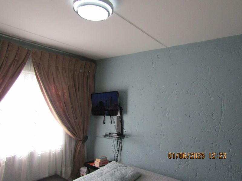 A bedroom featuring textured blue walls and a ceiling-mounted light fixture.