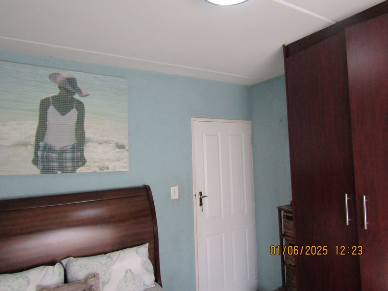 A bedroom featuring light blue walls and a dark wood built-in wardrobe.