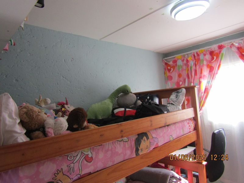 A bedroom featuring a textured wall finish and a central ceiling light fixture, currently utilized as a child's sleeping space.