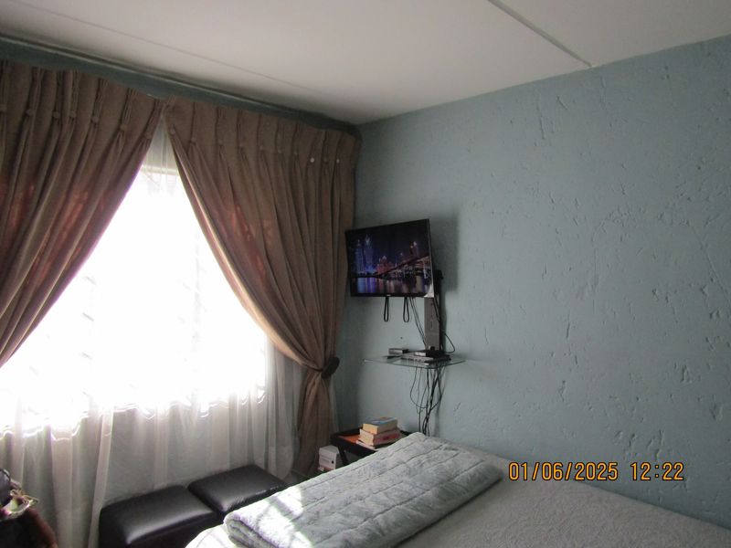 A bedroom featuring textured walls and a window with heavy curtains, providing a functional space for rest.