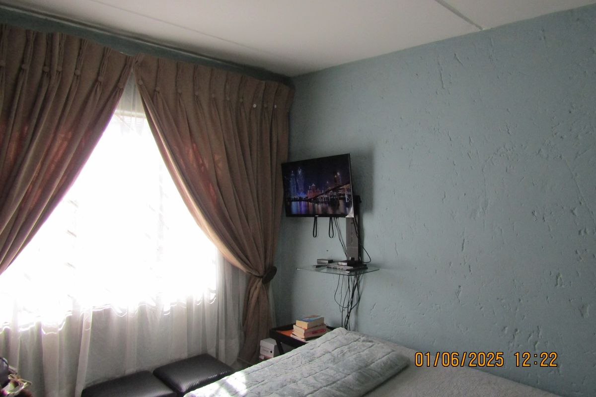 A bedroom featuring textured walls and a window with heavy curtains, providing a functional space for rest.