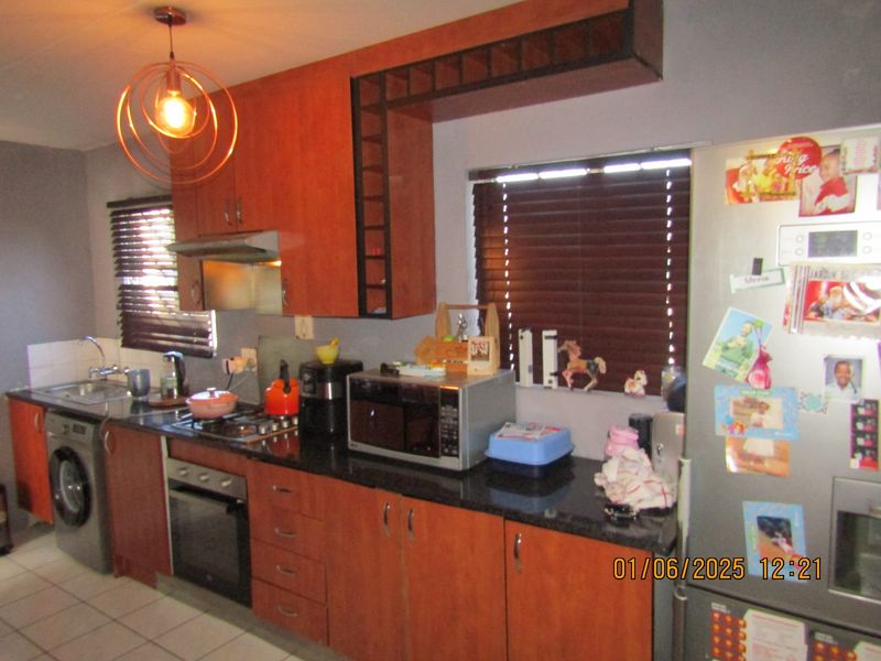 A functional kitchen featuring wood-finish cabinetry, granite countertops, a built-in oven with gas hob, and tiled flooring.