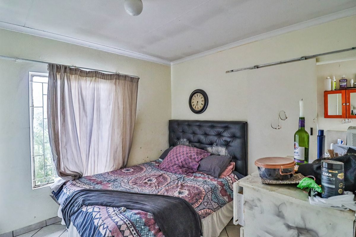 A bedroom featuring security bars on the window and coving detail. The room requires cosmetic updates including wall repairs and fresh paint.