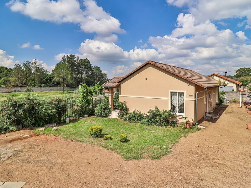 Rear view of the townhouse featuring a tiled roof, plastered exterior walls, and a private garden area with perimeter fencing.