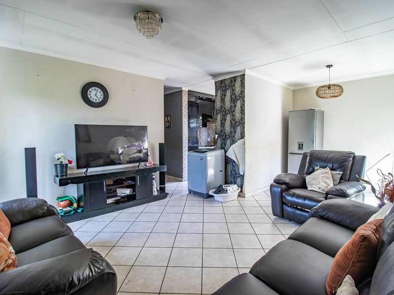 Open-plan living area featuring tiled flooring and ceiling lighting, offering a versatile space that could benefit from cosmetic updates and modern finishes.