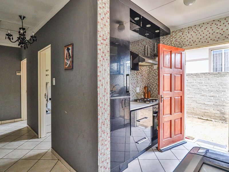 Compact kitchen featuring dark cabinetry, mosaic wall tiles, and direct access to an outdoor area.