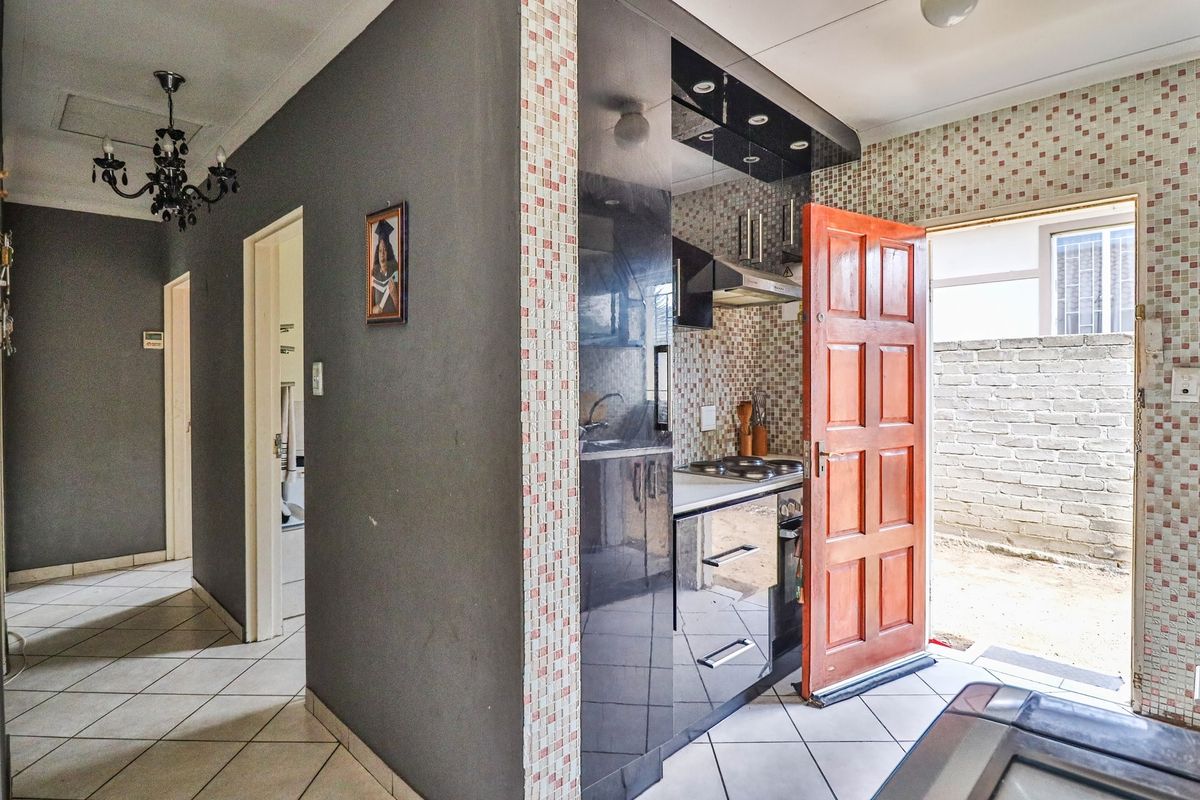 Compact kitchen featuring dark cabinetry, mosaic wall tiles, and direct access to an outdoor area.