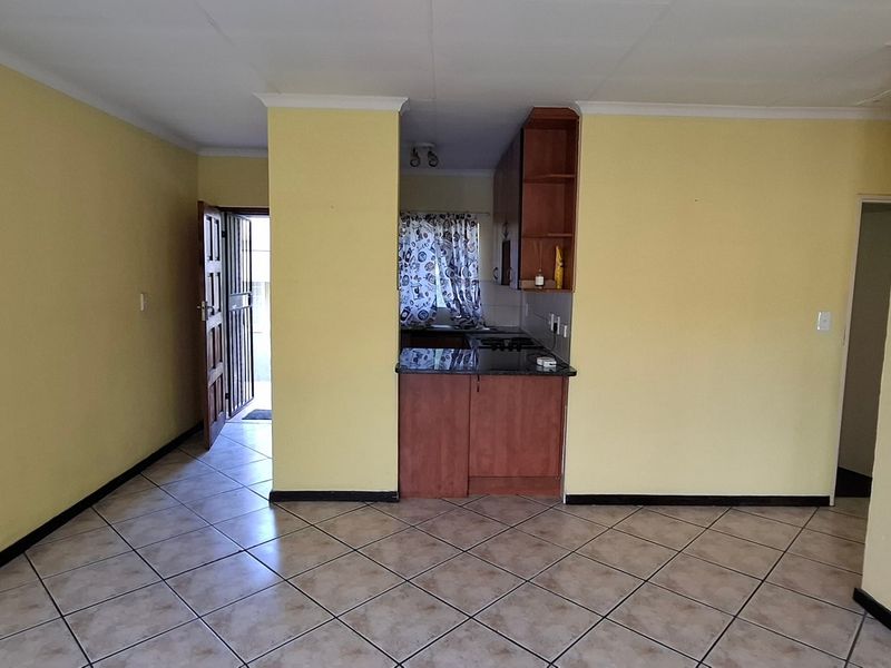 Open plan living area featuring tiled floors and a compact kitchen with built-in cabinetry and granite countertops.