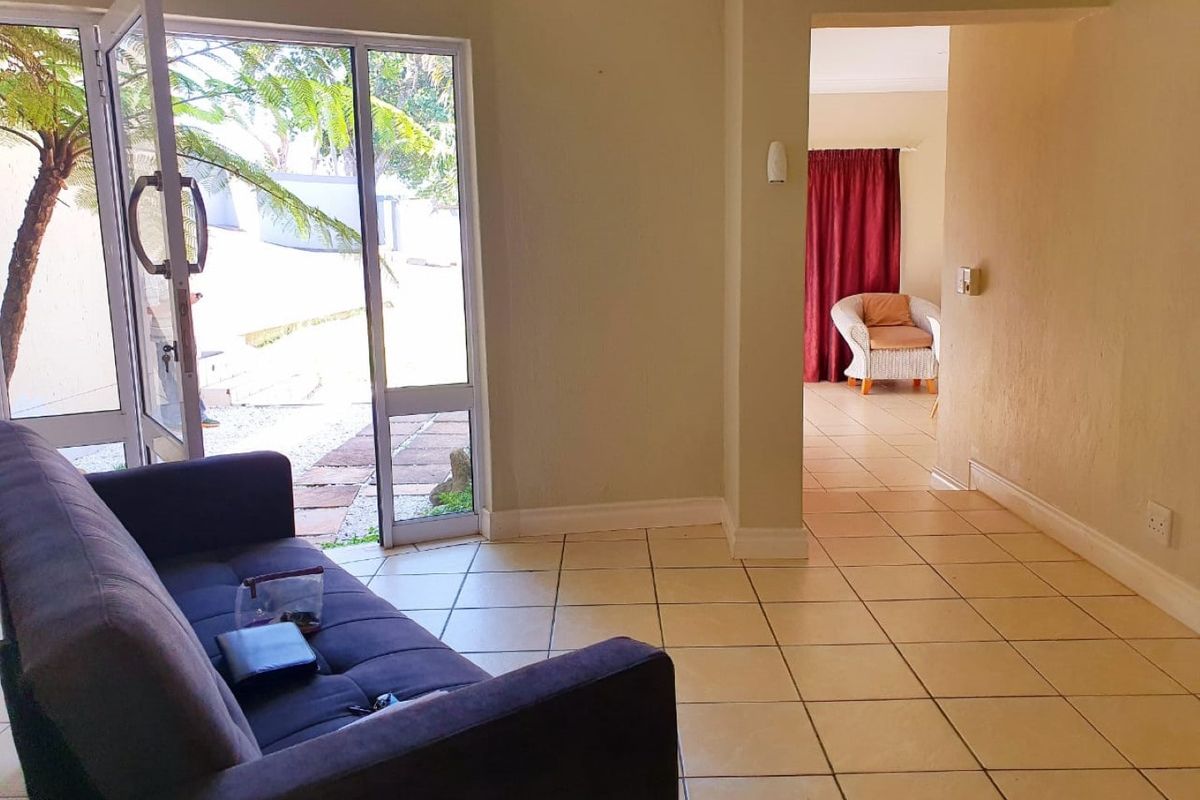 A living area featuring neutral tiled flooring and a large aluminium sliding door providing direct access to the outdoor space.