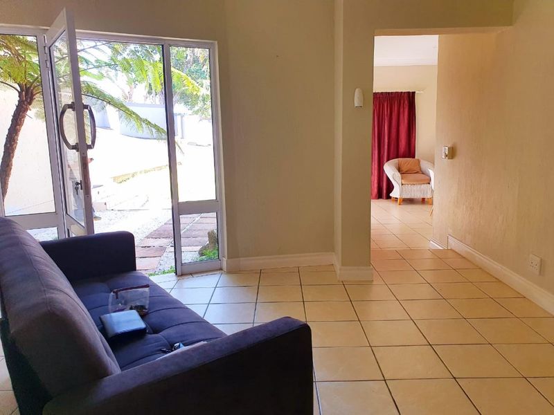A living area featuring neutral tiled flooring and a large aluminium sliding door providing direct access to the outdoor space.