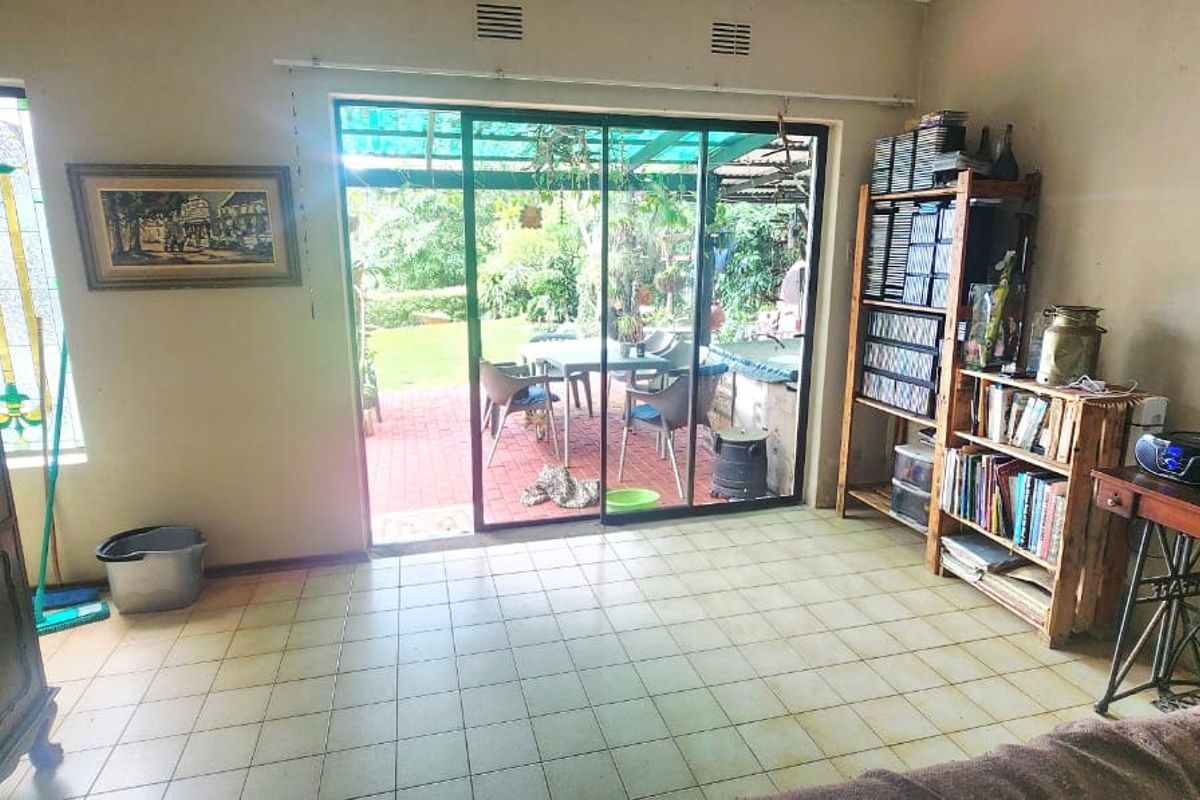 Living room featuring ceramic floor tiles, a decorative stained glass window, and sliding glass doors providing direct access to the rear patio.