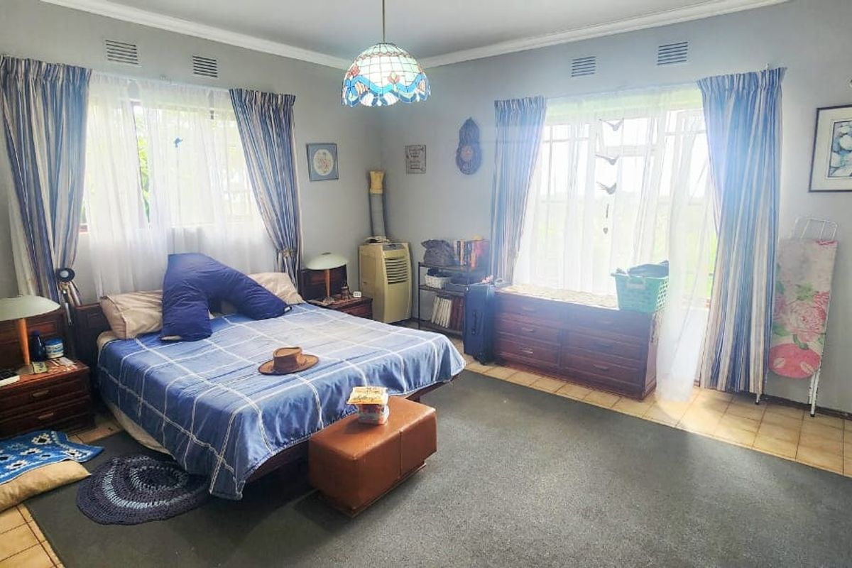 Spacious bedroom featuring dual windows, built-in cupboard storage, and a combination of tiled and carpeted flooring.