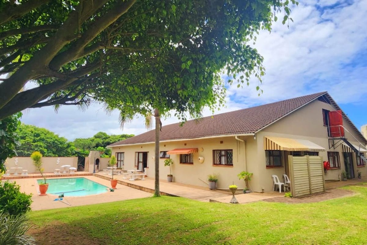 Rear exterior view of the commercial property featuring a swimming pool, paved patio area, and established garden surroundings.