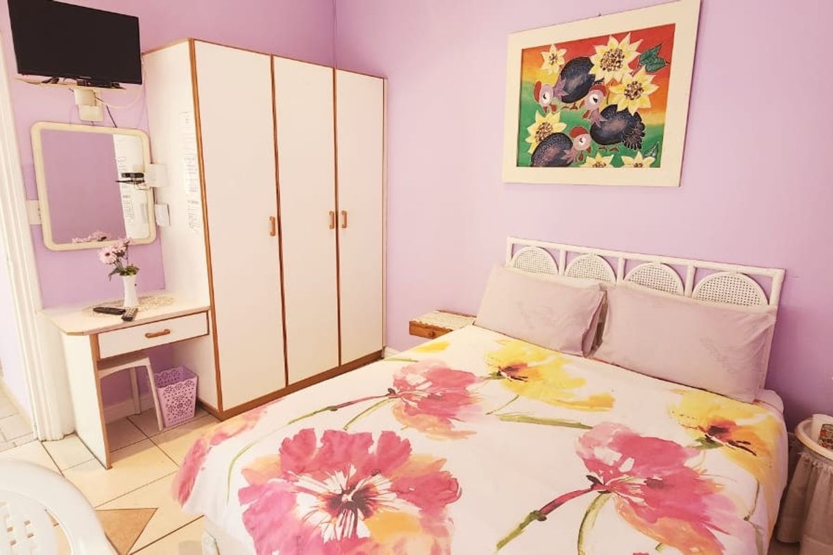 A bedroom featuring tiled flooring and a built-in wardrobe, presented in a functional, lived-in condition.