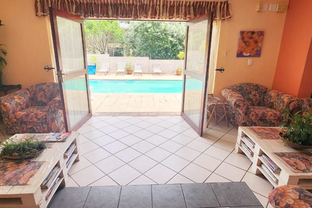 A waiting area with tiled flooring and double doors opening directly onto a swimming pool area.