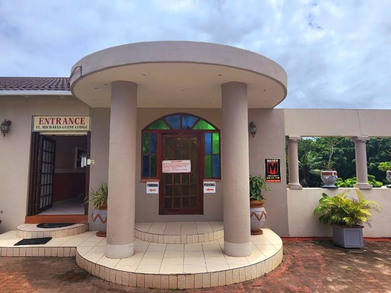 Front entrance of the commercial property featuring a covered porch with concrete columns, tiled steps, and a decorative stained glass door.