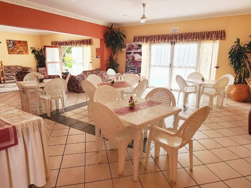 Spacious open-plan commercial dining area featuring tiled flooring, a built-in bar counter, and sliding glass doors providing access to the exterior.