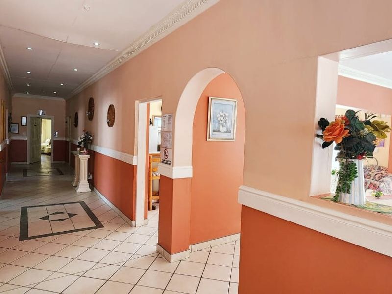 A spacious commercial hallway featuring ceramic tile flooring, decorative archways, and a two-tone wall finish with dado rail detailing.