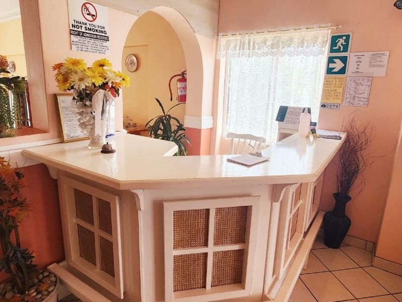 Commercial reception area featuring a built-in service desk, arched entryway, and tiled flooring in a functional, dated layout.