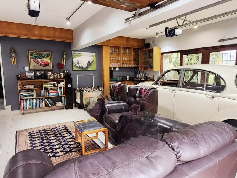 A spacious garage area featuring tiled flooring, track lighting, and built-in cabinetry, currently utilized as a multi-purpose living and storage space.
