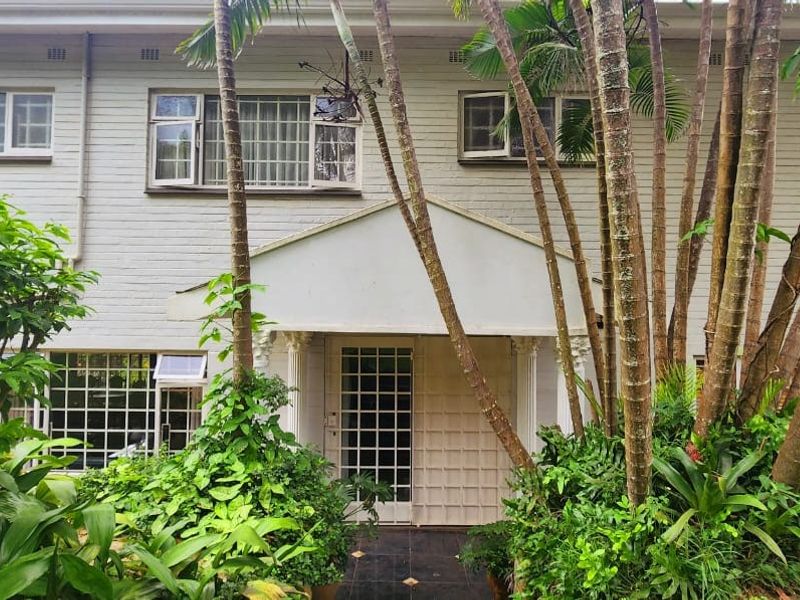 Front elevation of a two-story brick residence featuring a covered entrance porch, security-fitted windows, and established garden landscaping.