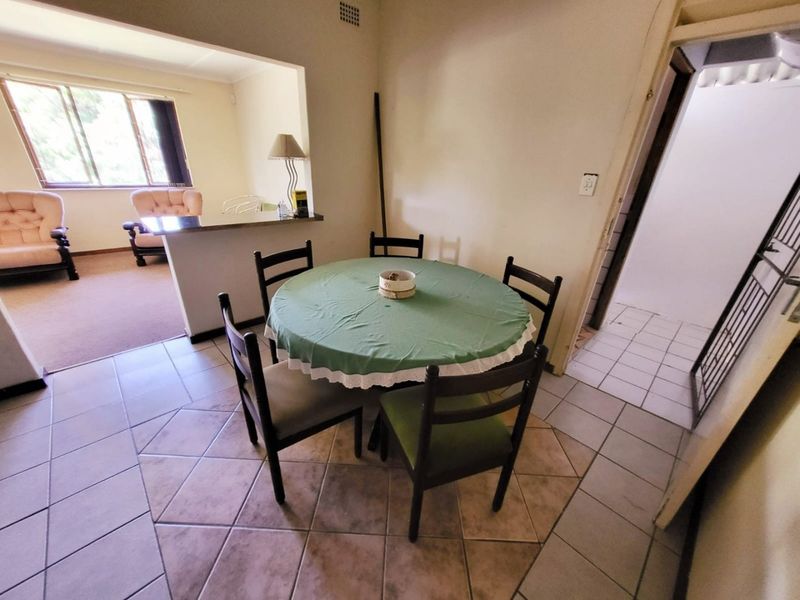 Open plan dining area featuring tiled flooring and a breakfast bar connecting to the adjacent living space.